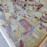 Small Art Deco bedside table in light wood with a terrazzo effect top.