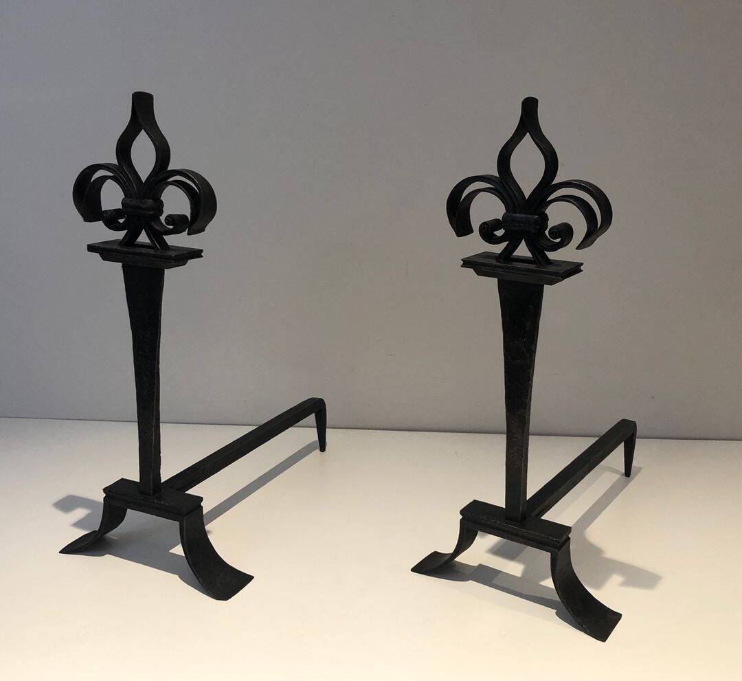Important pair of wrought iron andirons with torch in heraldic fleur-de-lis design.