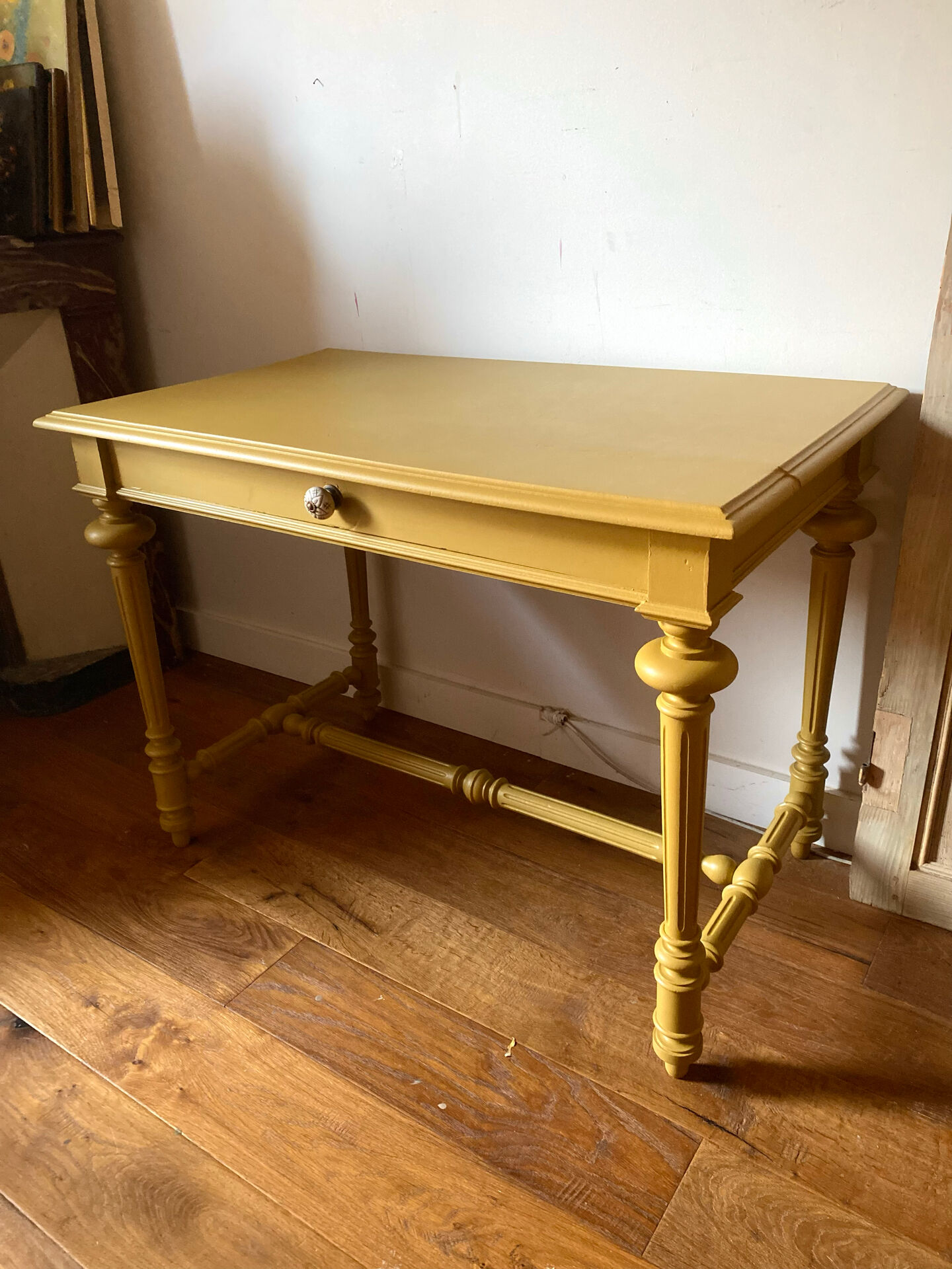 Desk table from the late 19th century, painted mustard, with turned stretcher.