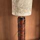 Table lamp with a solid wood printing roll and floral lampshade.