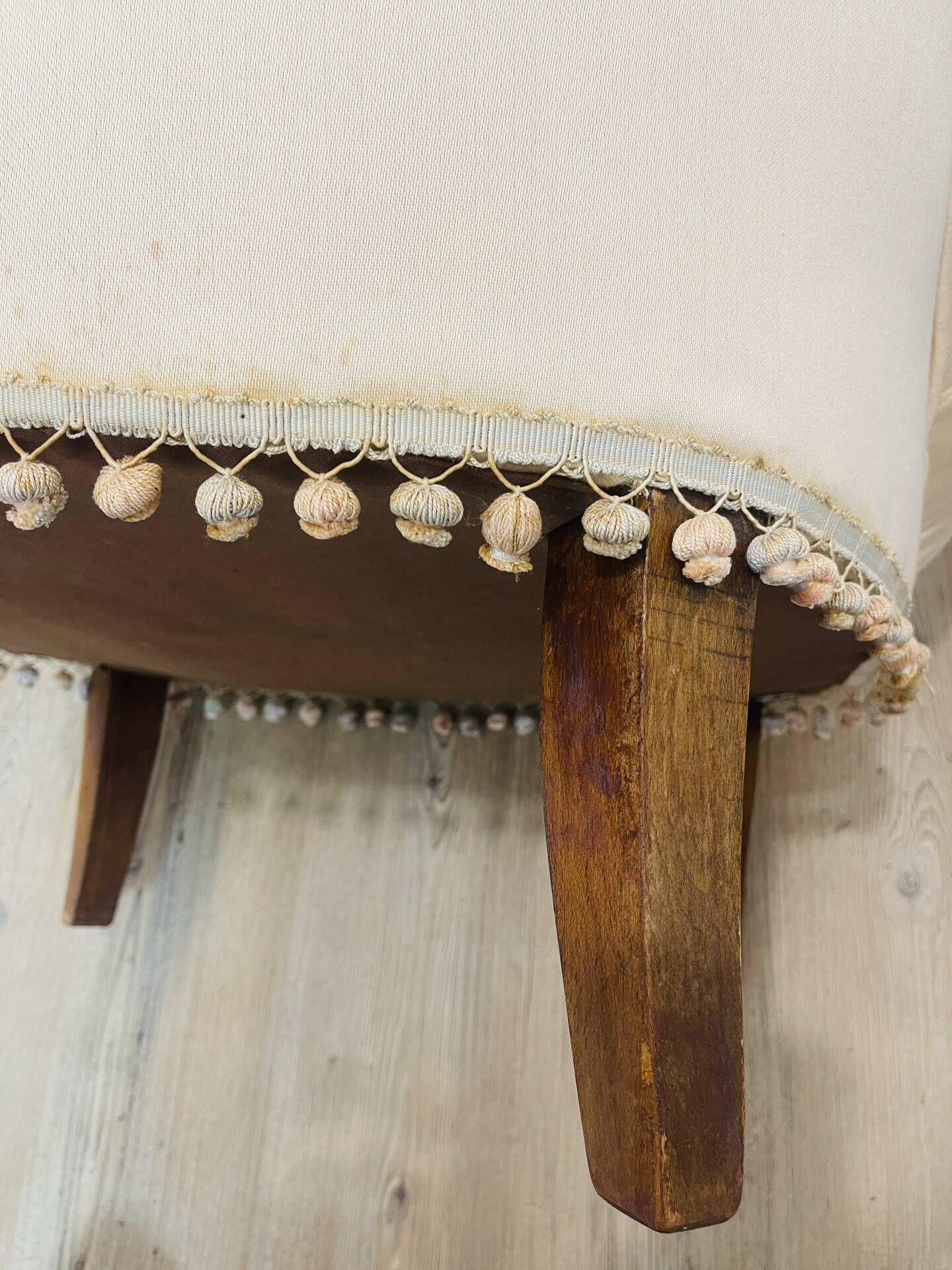Pale pink upholstered armchair with wooden legs.
