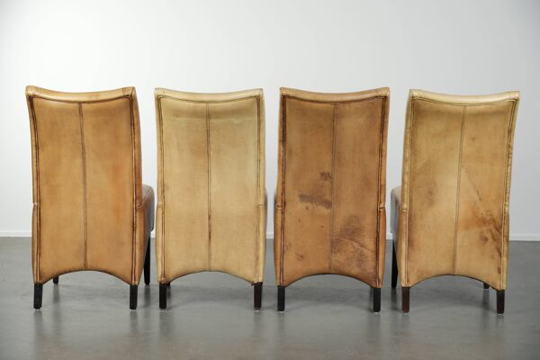Ensemble de quatre chaises de salle à manger en cuir de vache avec un siège confortable et un dossier haut.