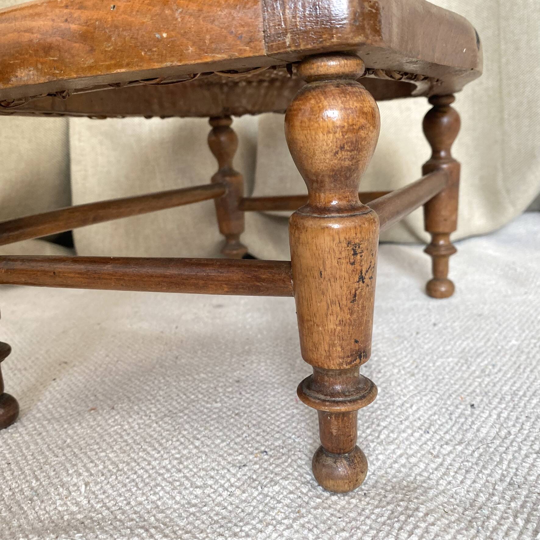 Low wooden stool with caning, footrest.