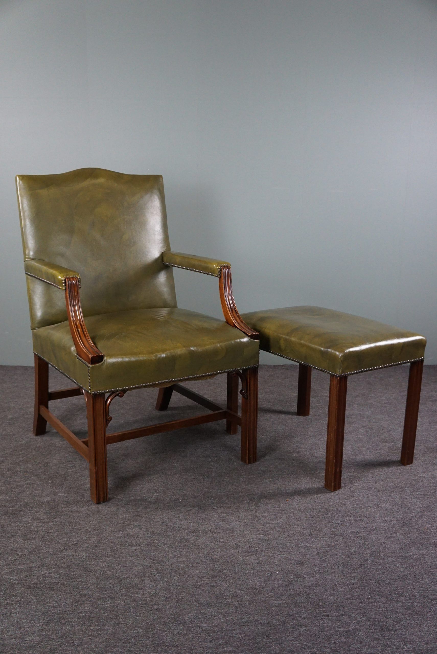 Elegant armchair and footrest in English green leather