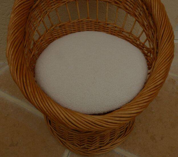 Wicker armchair with a high back and its boucle fabric cushion.