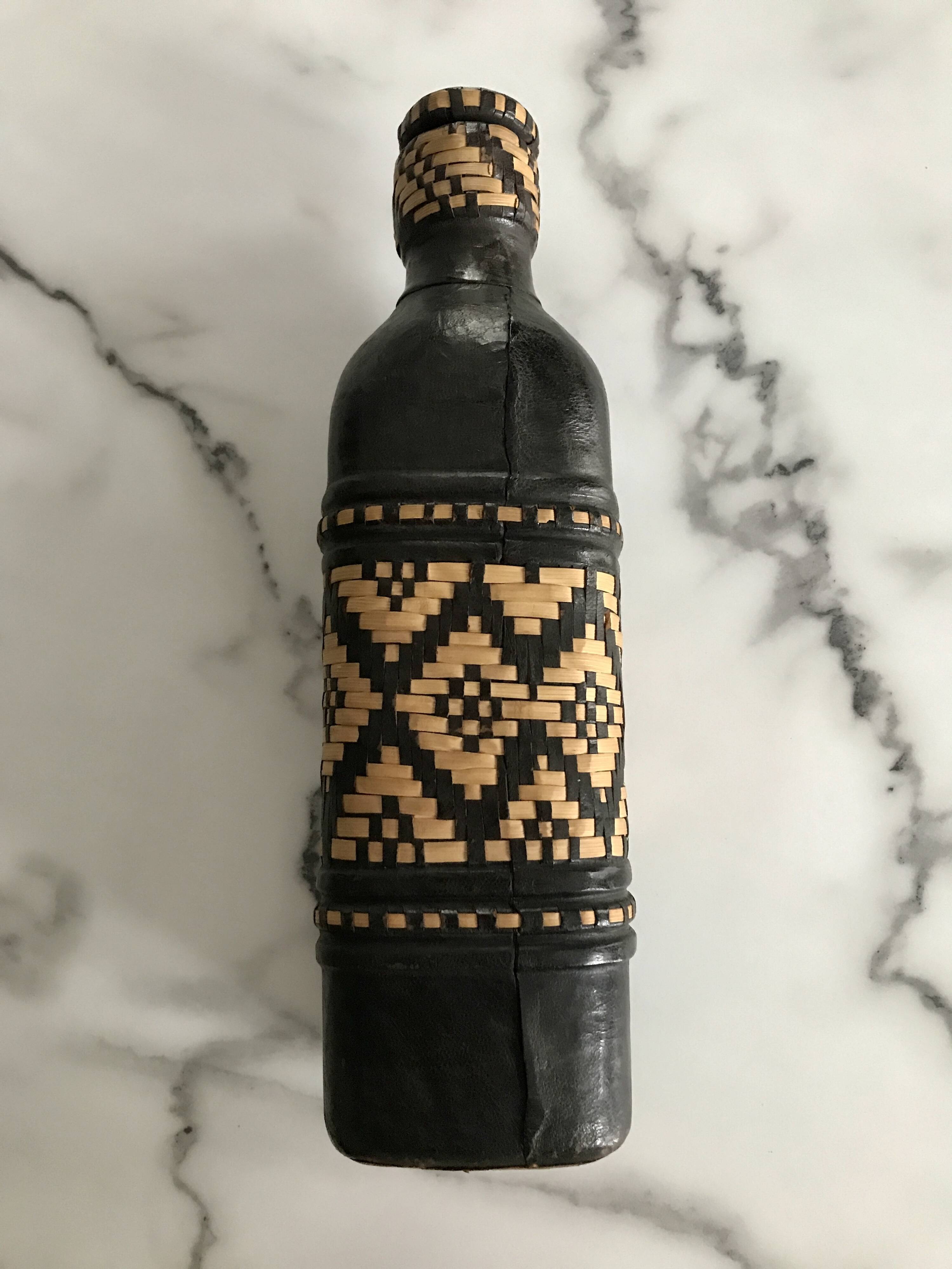 Ethnic decorative bottle in leather and raffia braiding