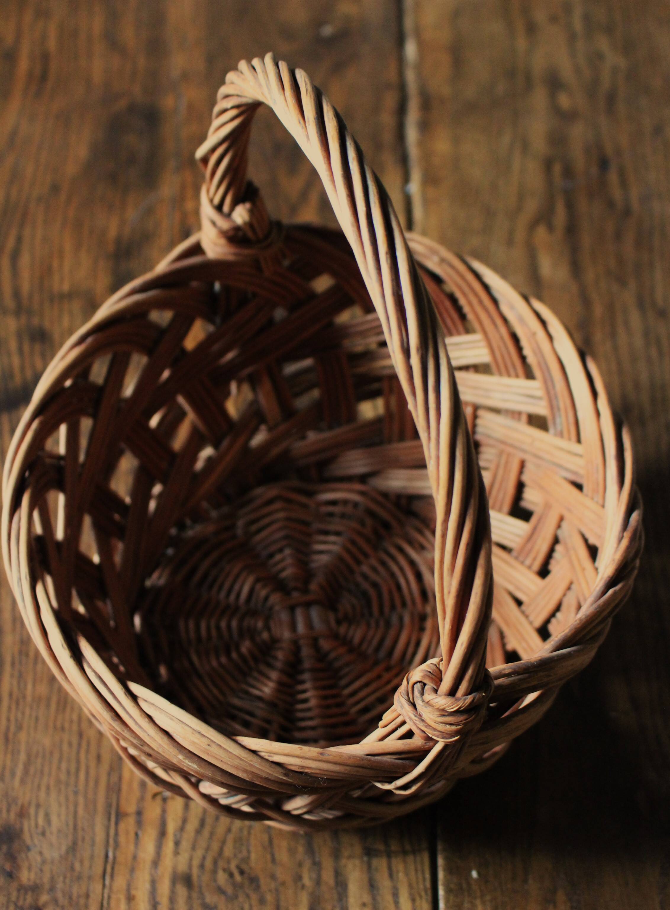 Round woven dark wicker basket with openwork vintage handle