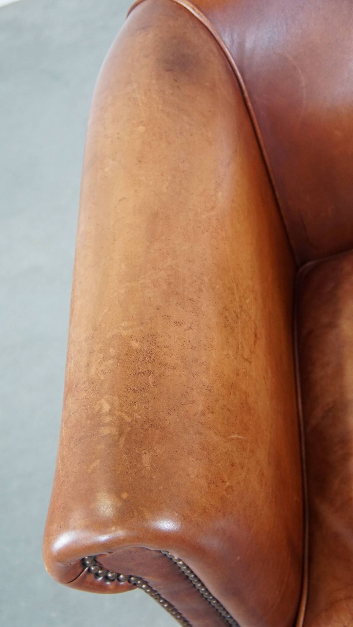 Cognac-colored cow leather club chair finished with decorative nails in English style