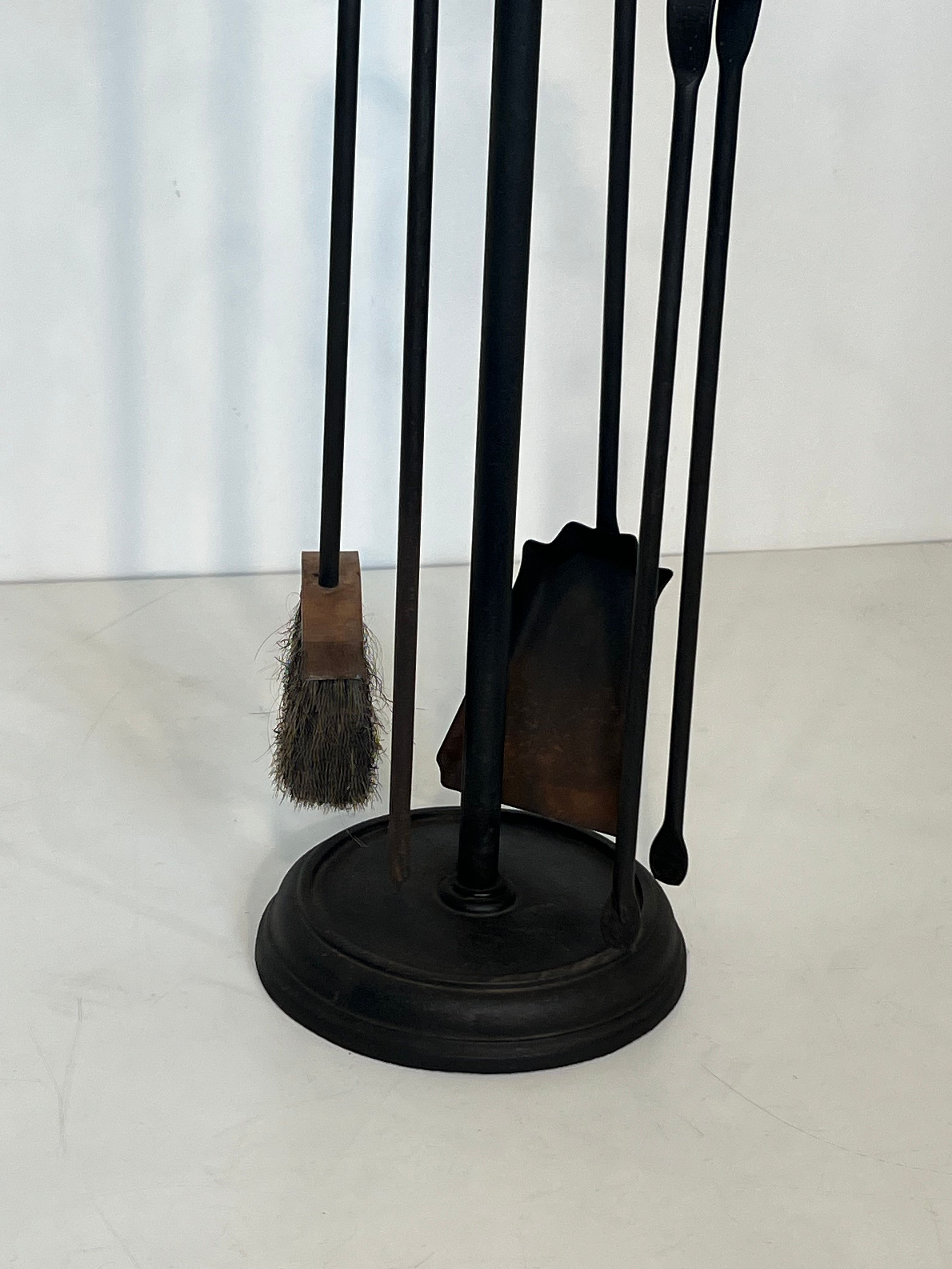 Neoclassical-style fire accessory in black lacquered metal and brass with fleur-de-lis.