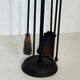 Neoclassical-style fire accessory in black lacquered metal and brass with fleur-de-lis.