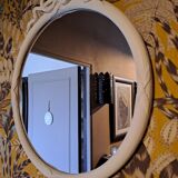 Round mirror in carved wood with at the top a ribbon forming a knot in cream color