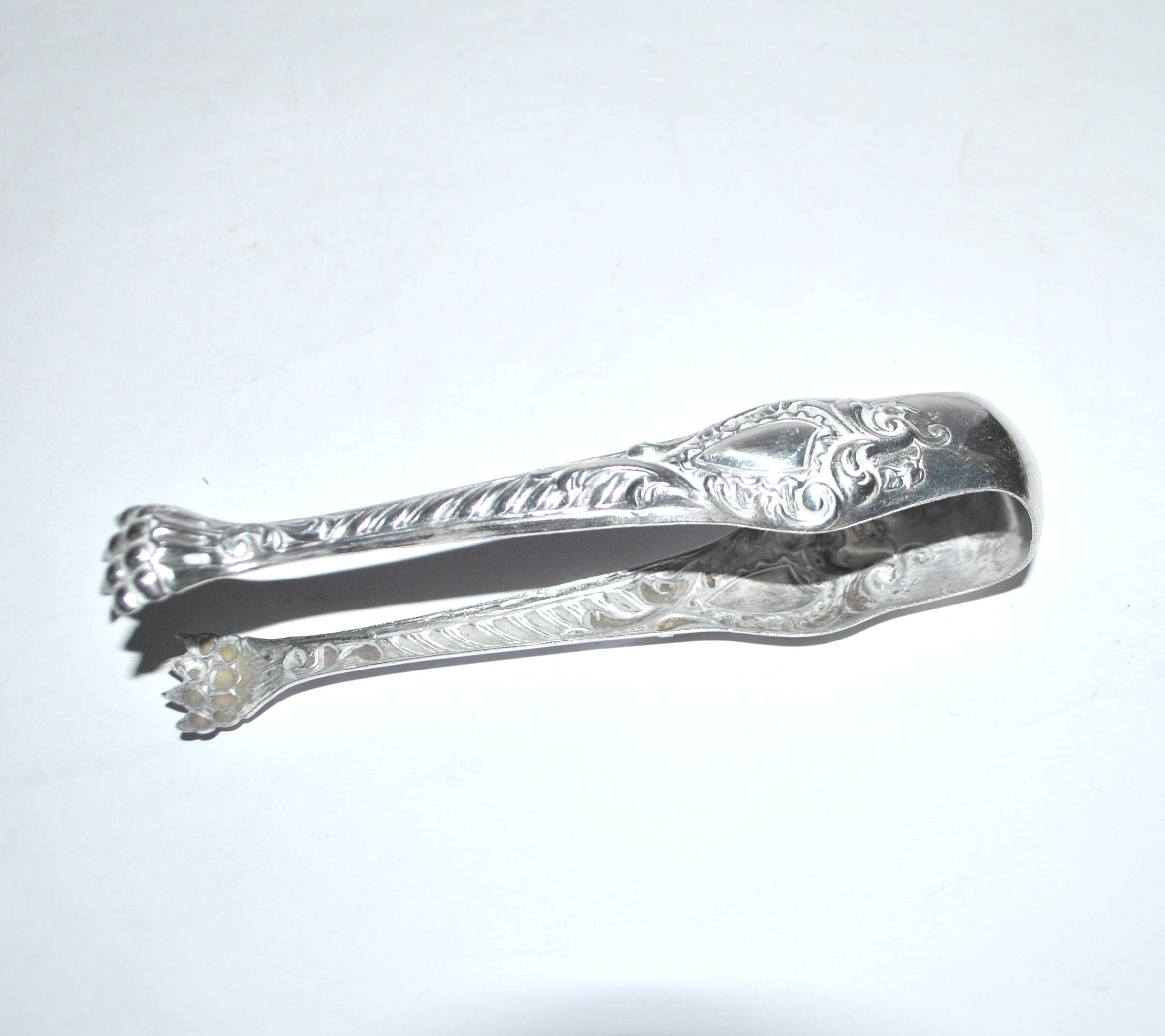Rocaille sugar tongs in silver metal with lion claw medallion