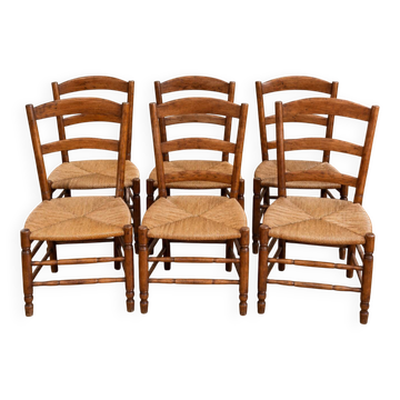 Set of six rustic chairs in natural wood with straw seats.