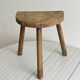 Small antique tripod stool in light wood, half-moon seat.