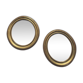 A pair of oval, gold wooden mirrors.
