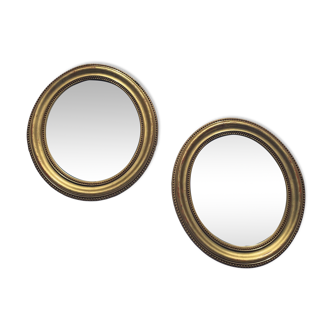 A pair of oval, gold wooden mirrors.