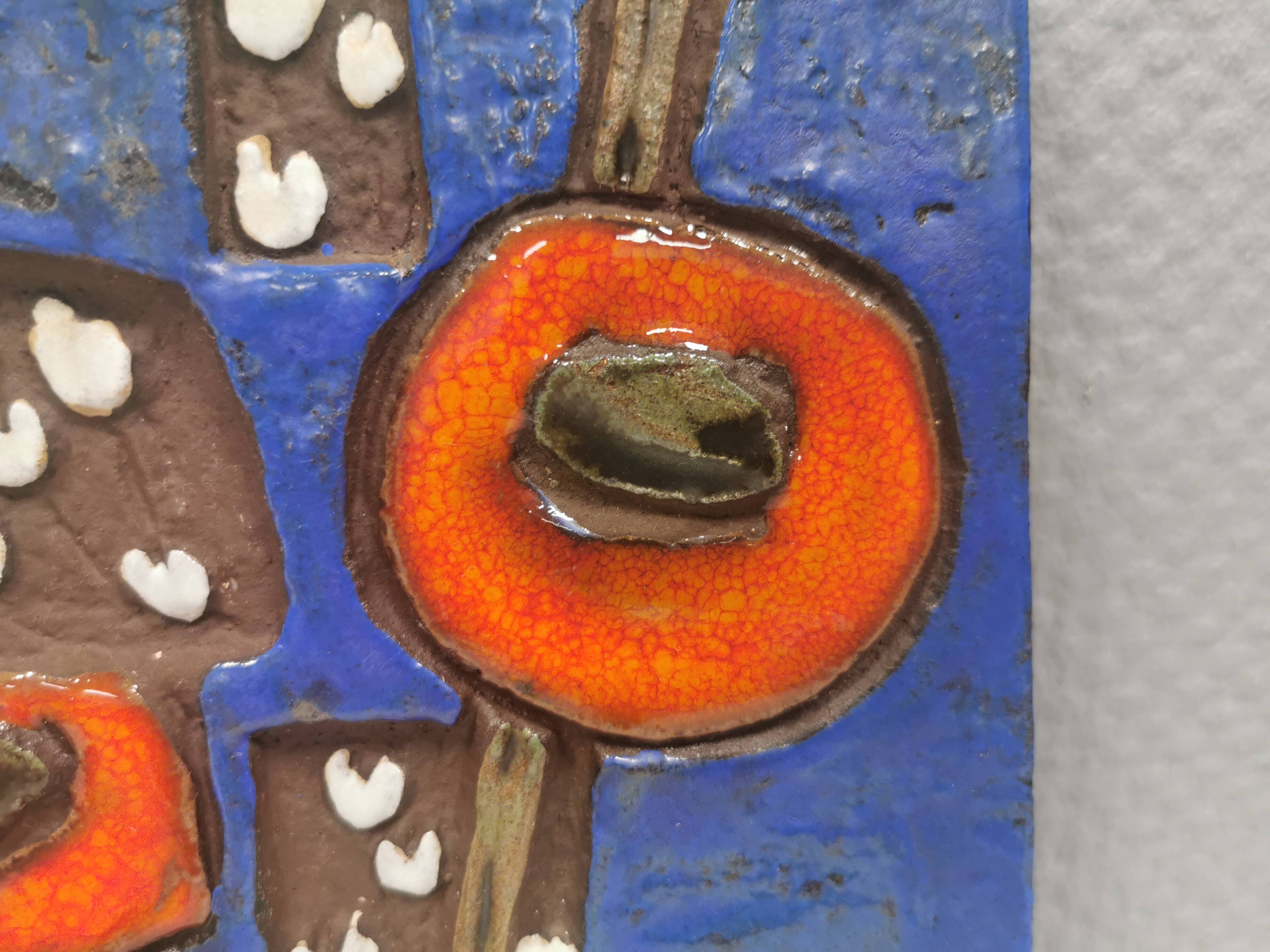 Ceramic relief in attractive blue with a motif of white/red flowers.