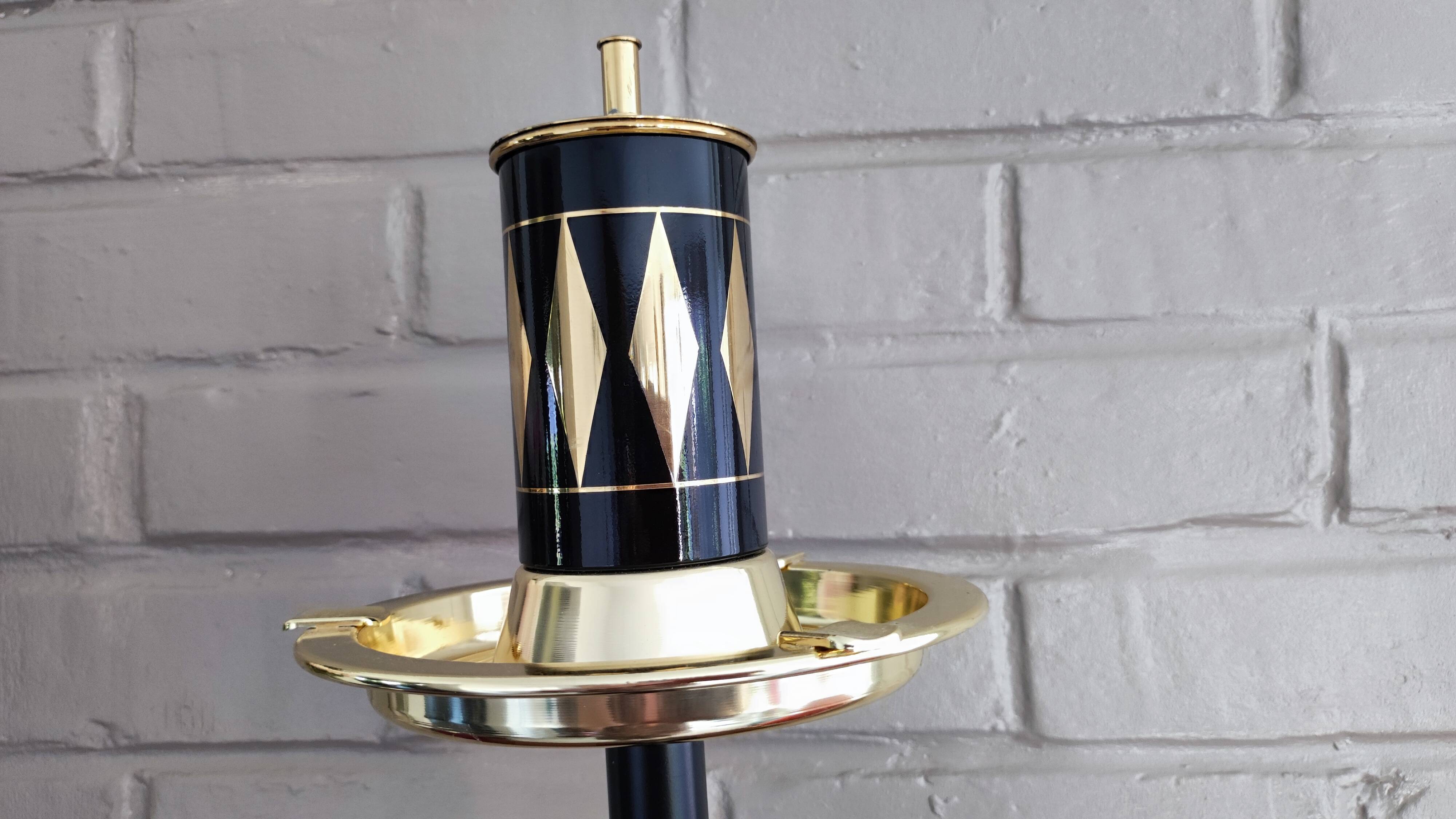 Vintage floor ashtray with a gold and black metal cigarette dispenser.