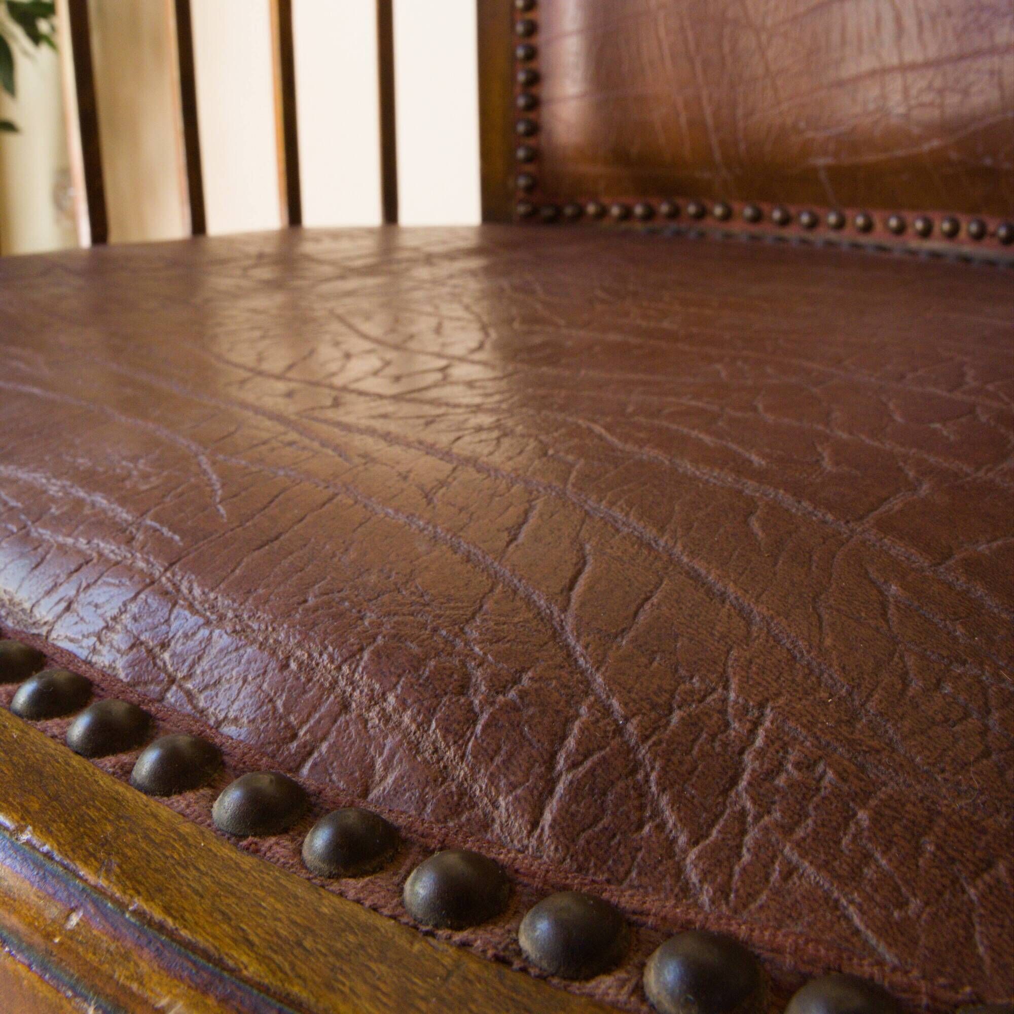 Antique armchair in solid wood and patinated brown leather, early 20th century.