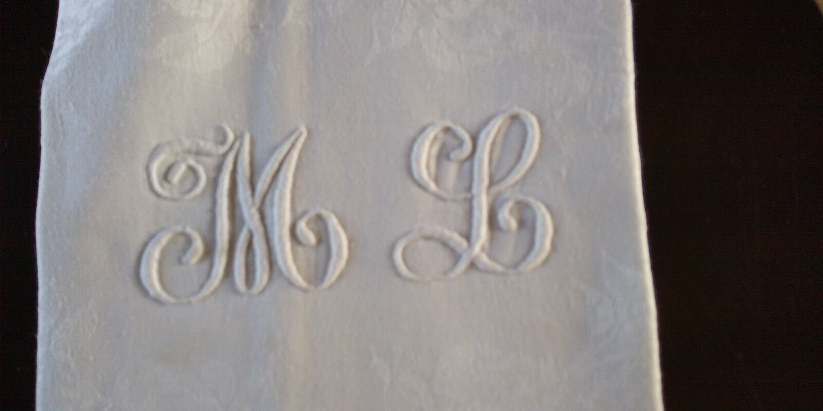 12 large antique damask towels with floral decoration and embroidered with the ML monogram