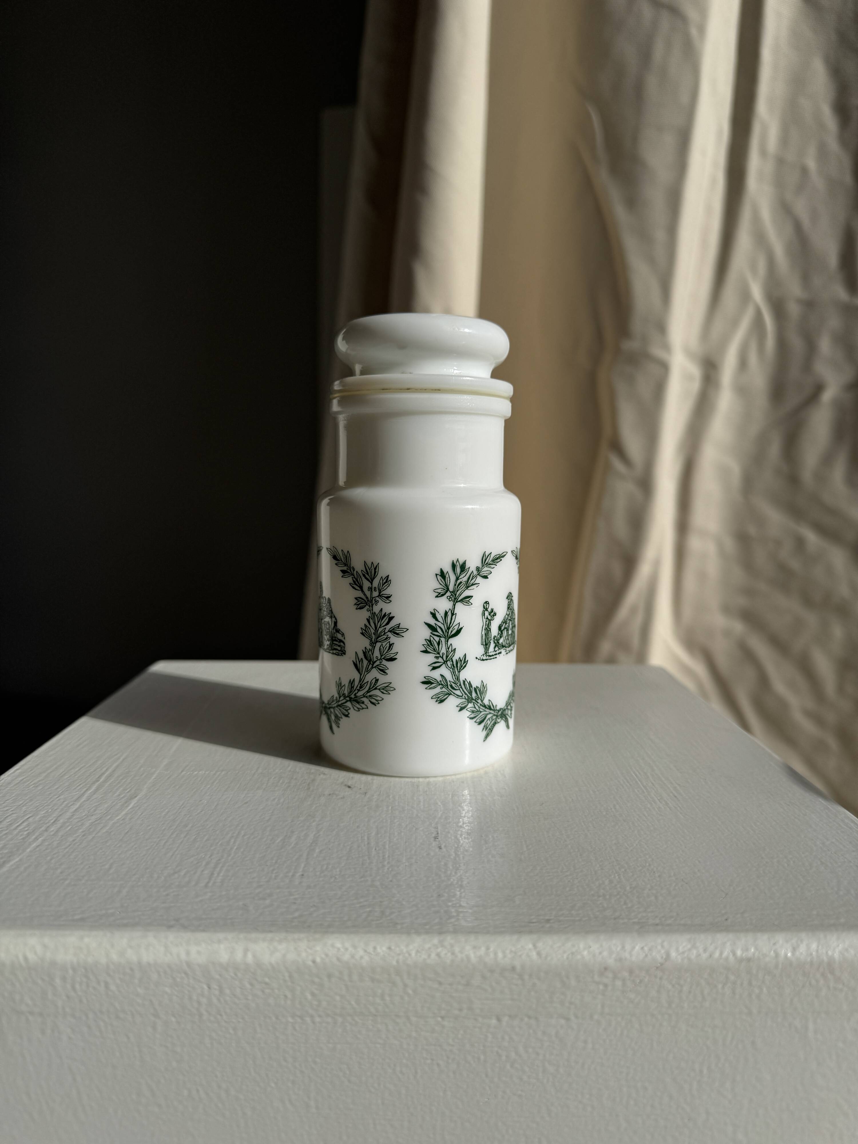A pair of white glass bottles with Italian green patterns.