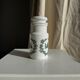 A pair of white glass bottles with Italian green patterns.
