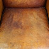 Subtle sheepskin wing chair in good condition on brass front wheels