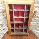 Old hanging display case with 15 wooden boxes, red background + vintage glass door