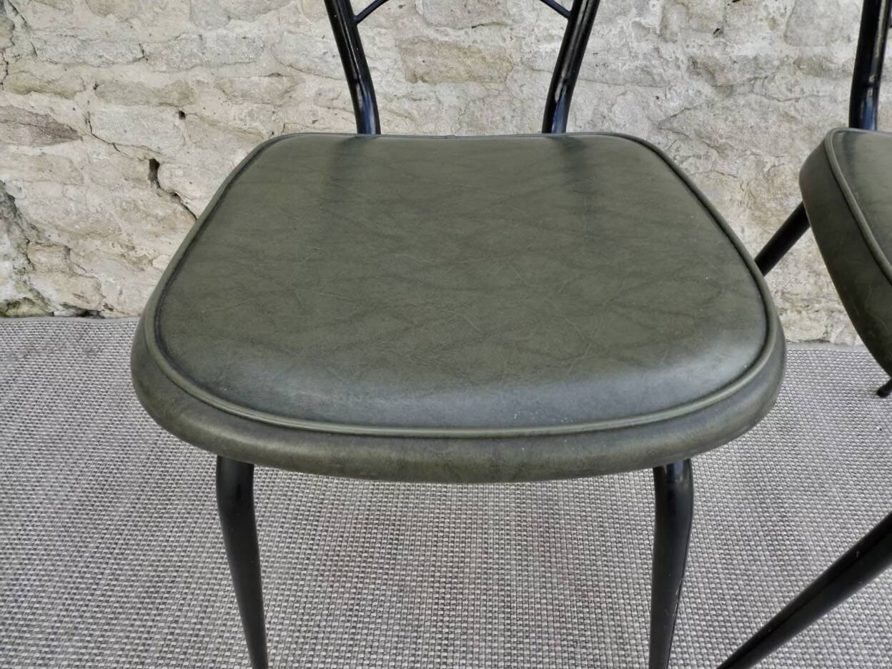 Black metal chairs with khaki faux leather seats, circa 1960.