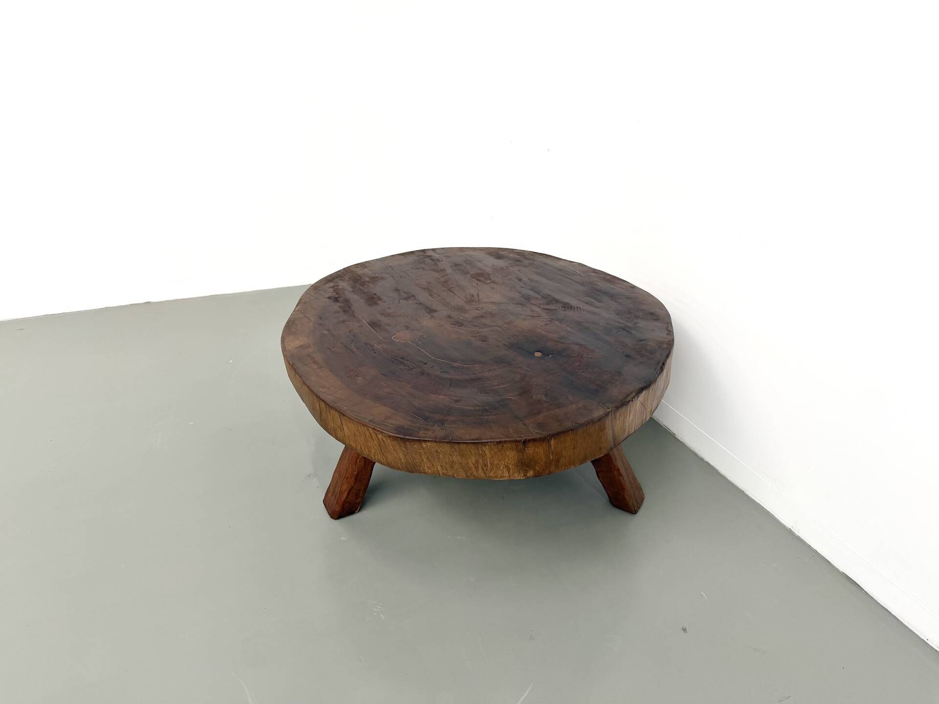 Brutalist coffee table in solid teak, monolithic slab, tripod base.