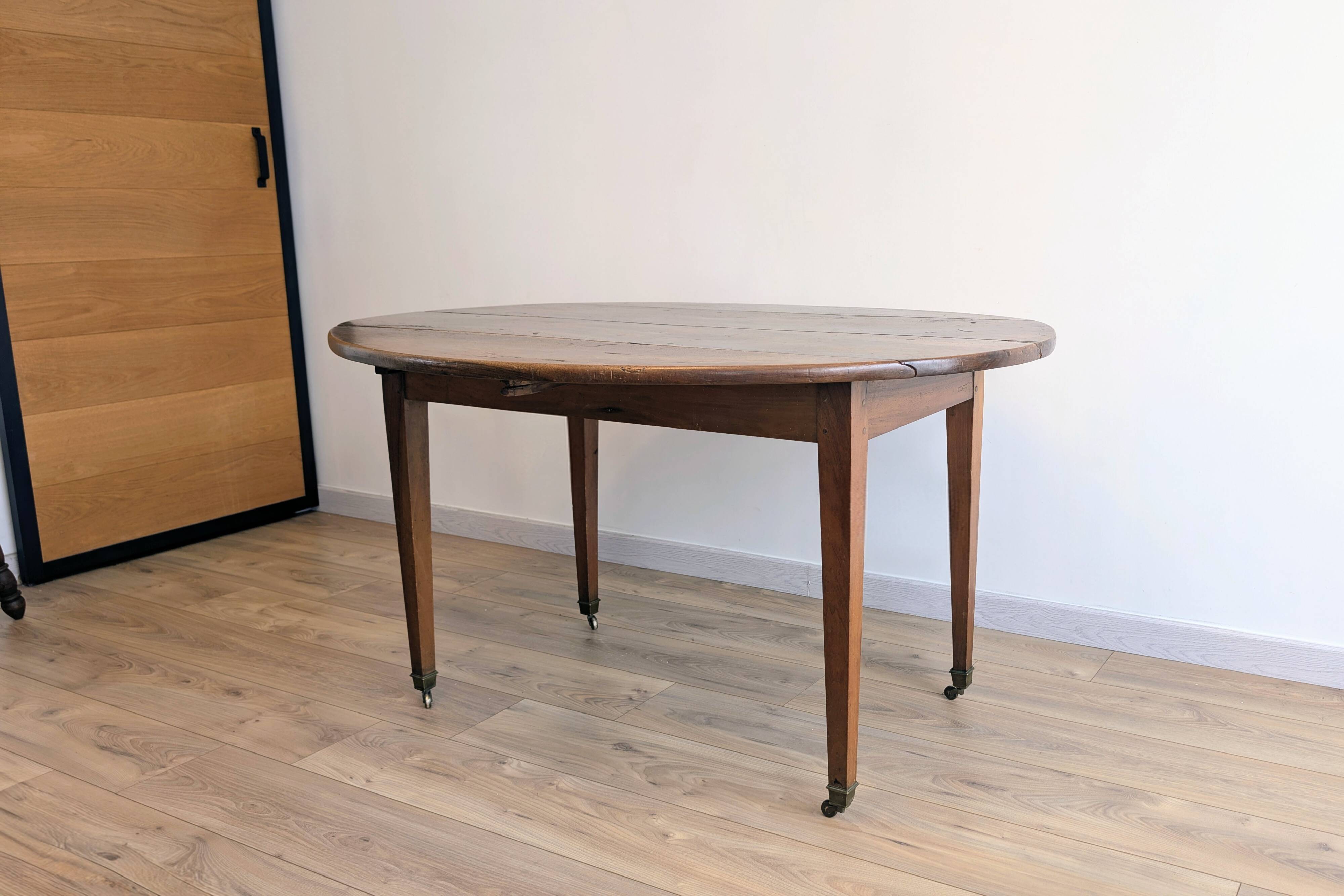Antique wooden folding table with a patina and brass wheels.