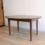 Antique wooden folding table with a patina and brass wheels.