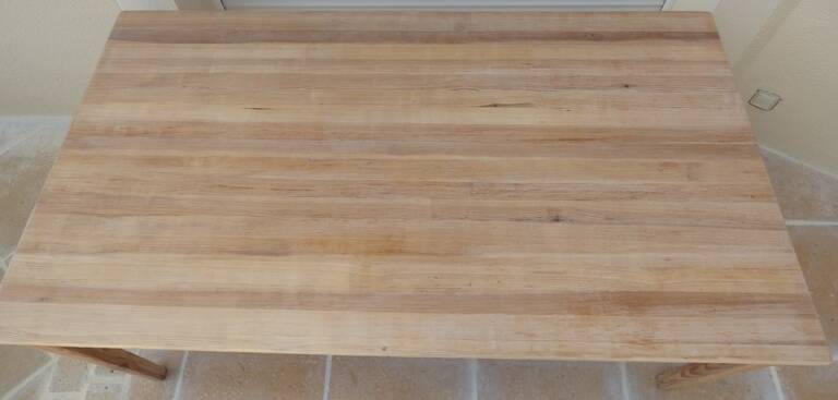 Large natural wood table with rectangular top supported by legs