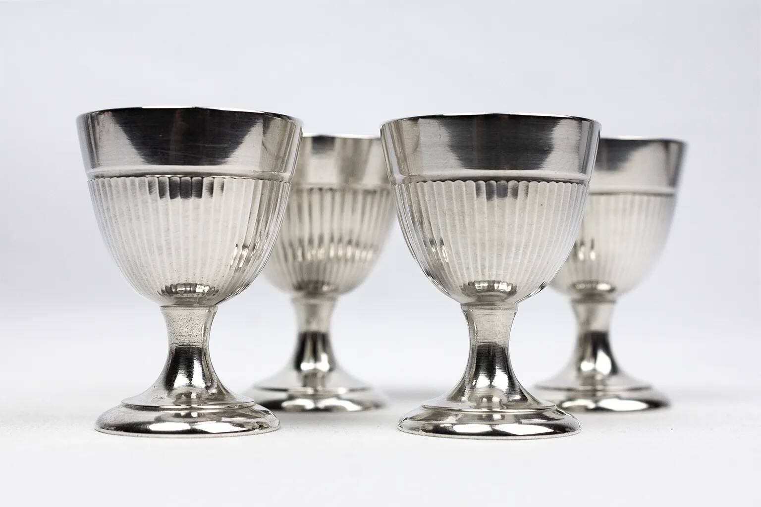 Four silver-plated Christofle egg cups with fluted sides.
