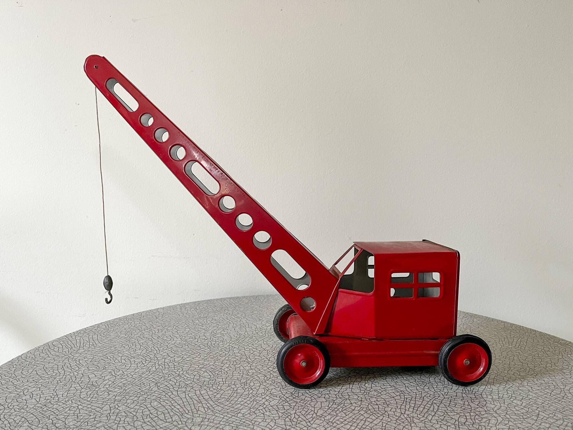 Grue de chantier rouge en tôle datant des années 60 avec mécanisme manuel
