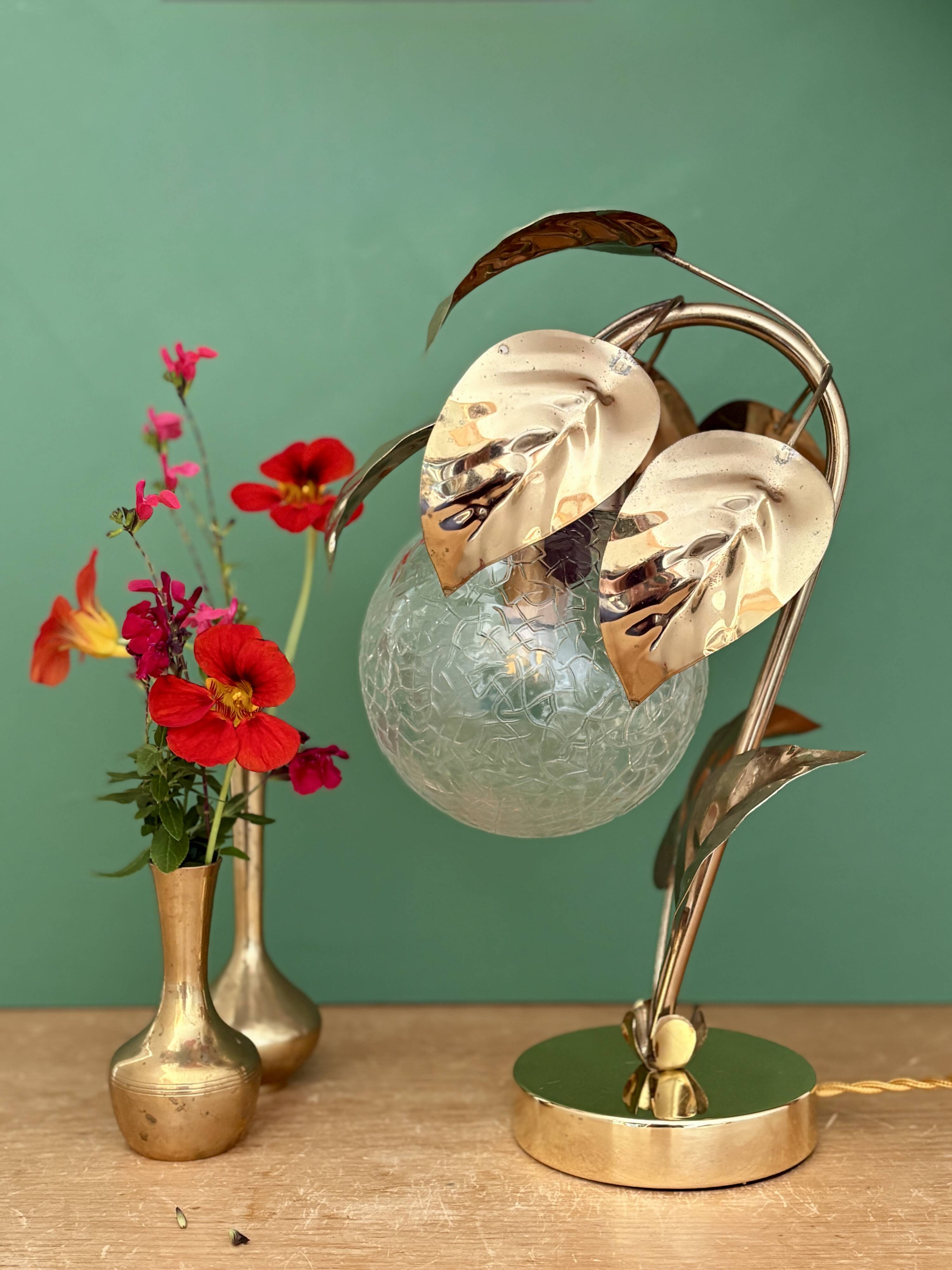 Vintage lamp with brass leaf design and transparent glass globe.