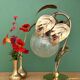 Vintage lamp with brass leaf design and transparent glass globe.