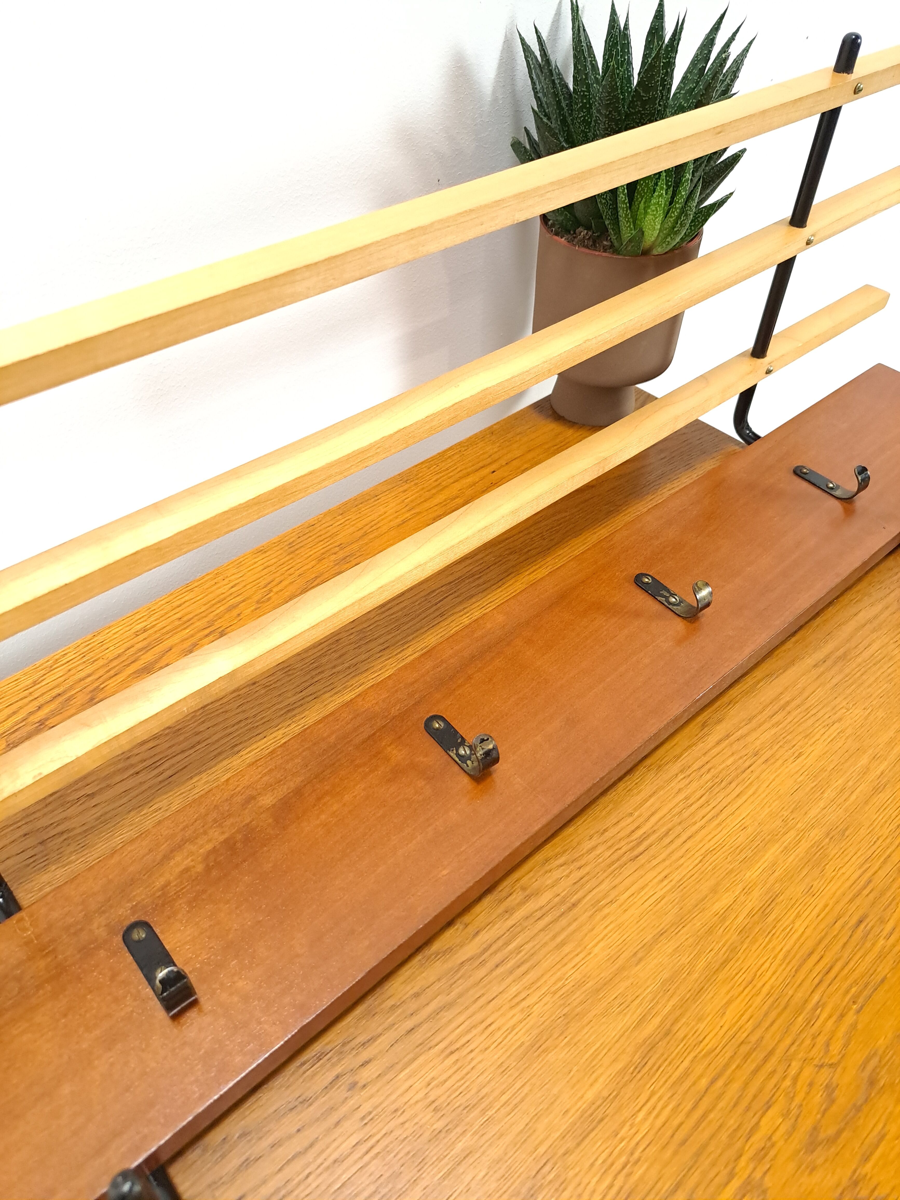 Vintage wall coat rack with black hooks and light wood