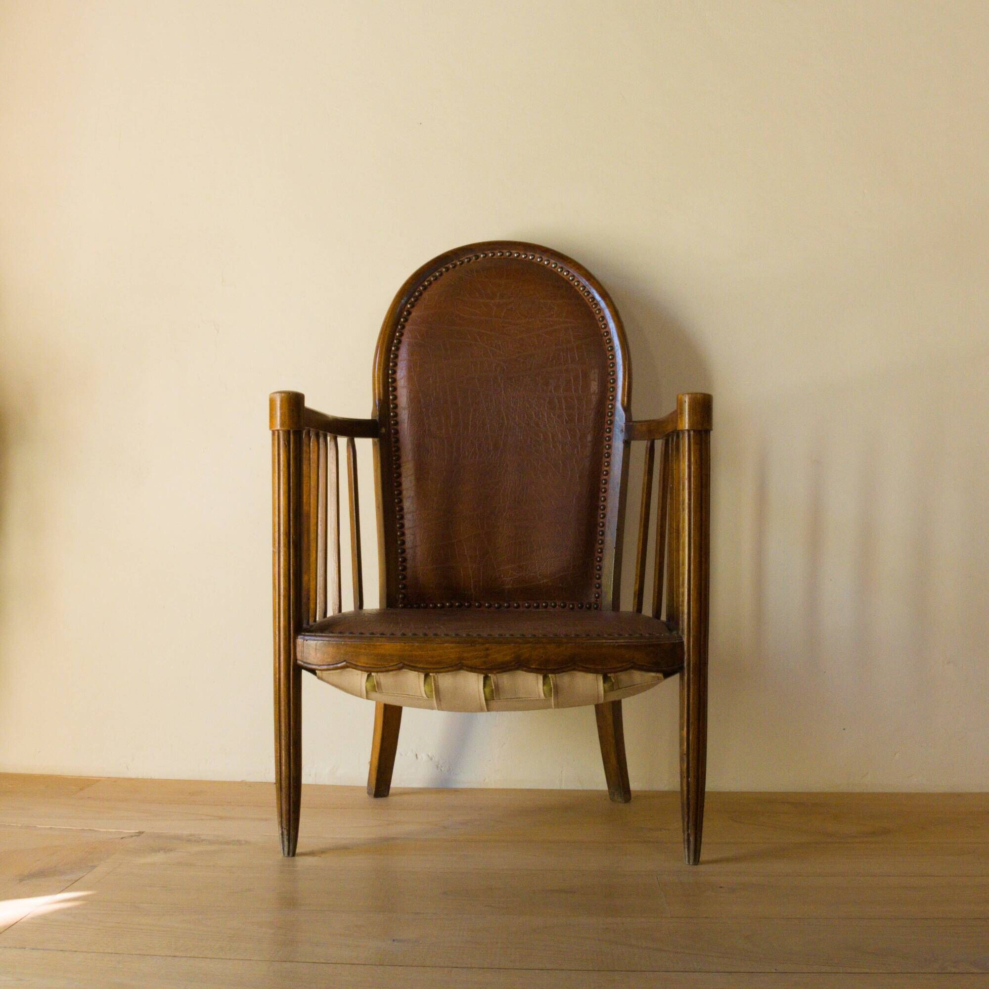 Antique armchair in solid wood and patinated brown leather, early 20th century.