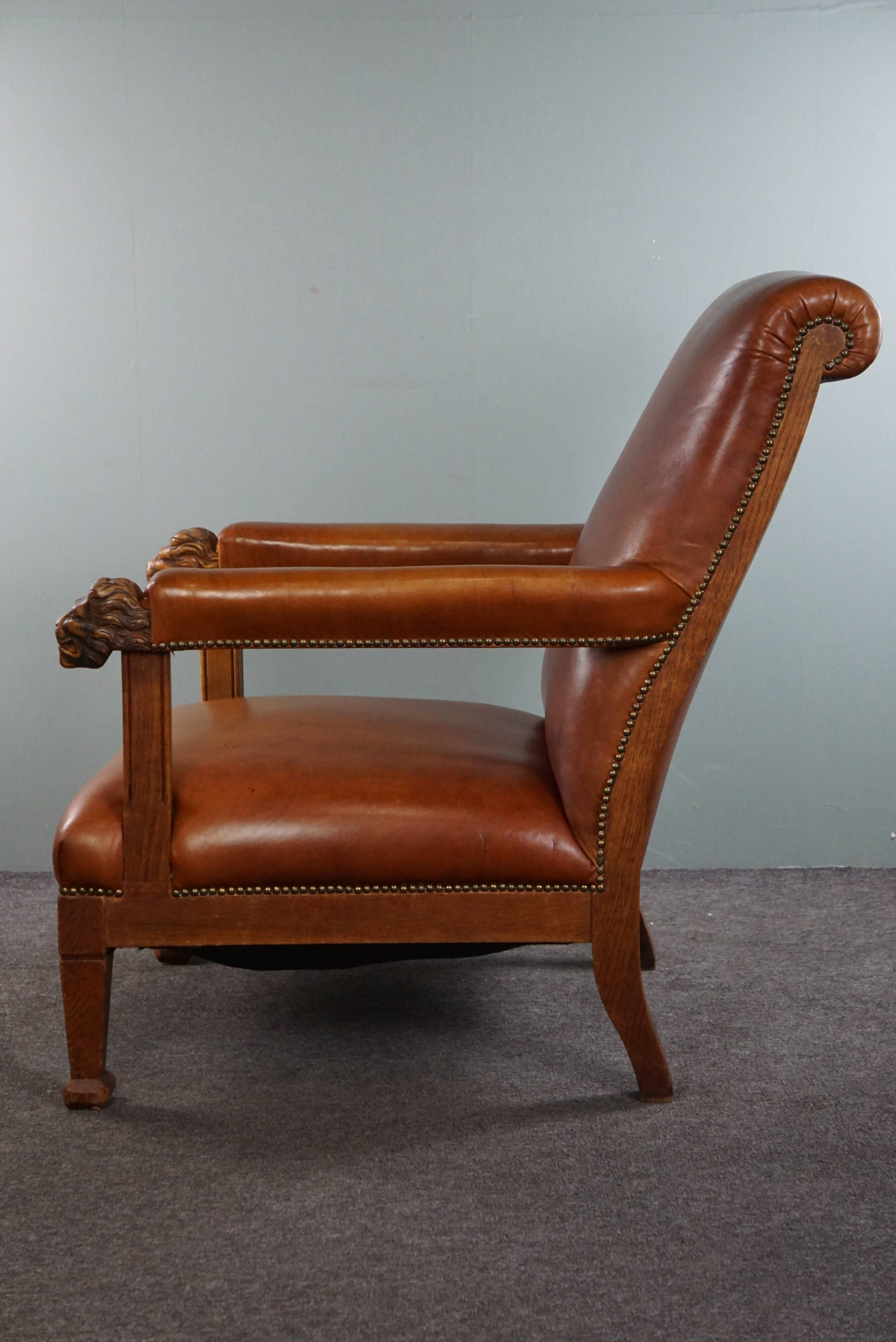 Armchair with lion heads reupholstered in cognac-colored cowhide leather