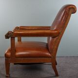 Armchair with lion heads reupholstered in cognac-colored cowhide