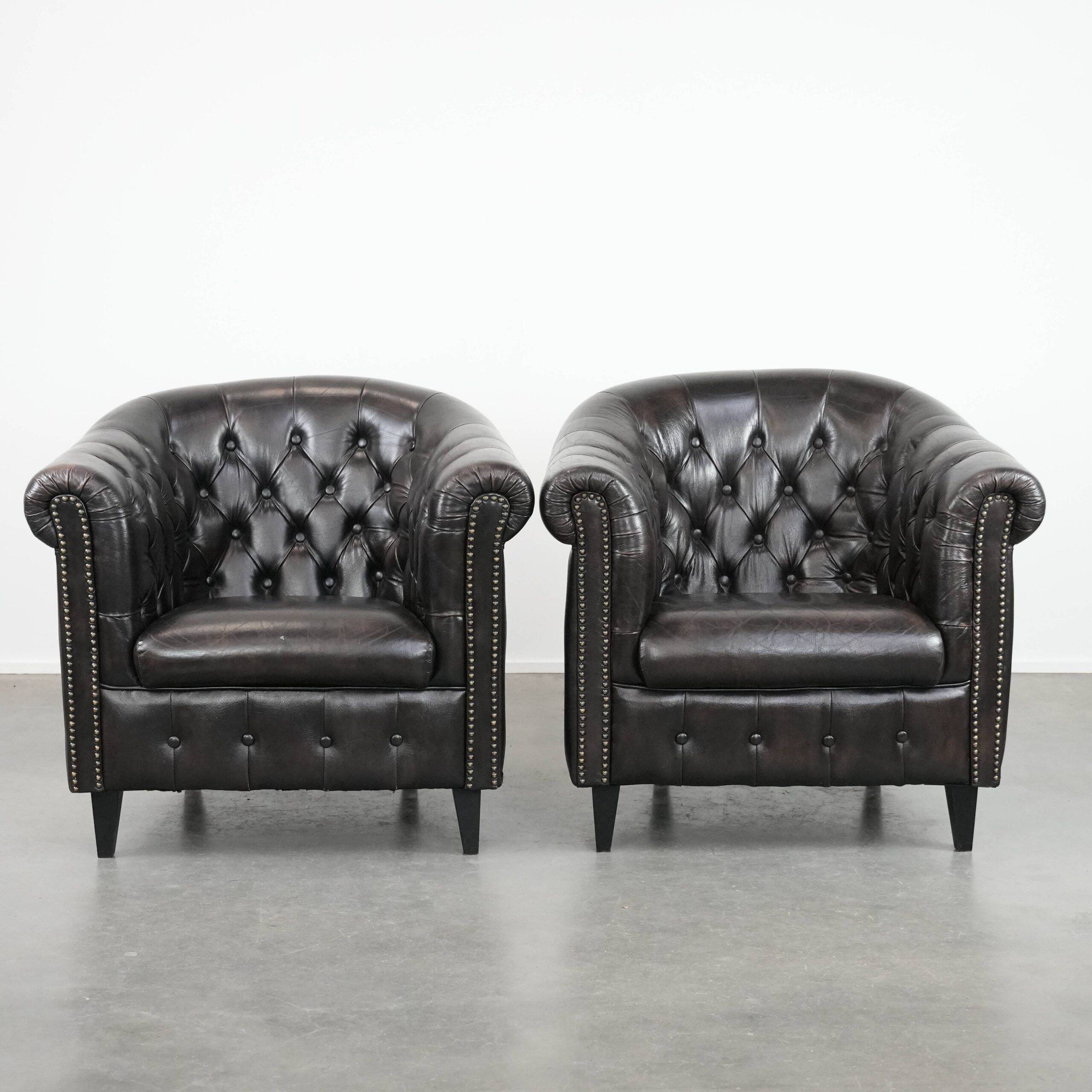 Ensemble de deux luxueux fauteuils club Chesterfield en cuir de vachette noir.