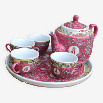 Chinese pink mu shou teapot and its cups on a tray.