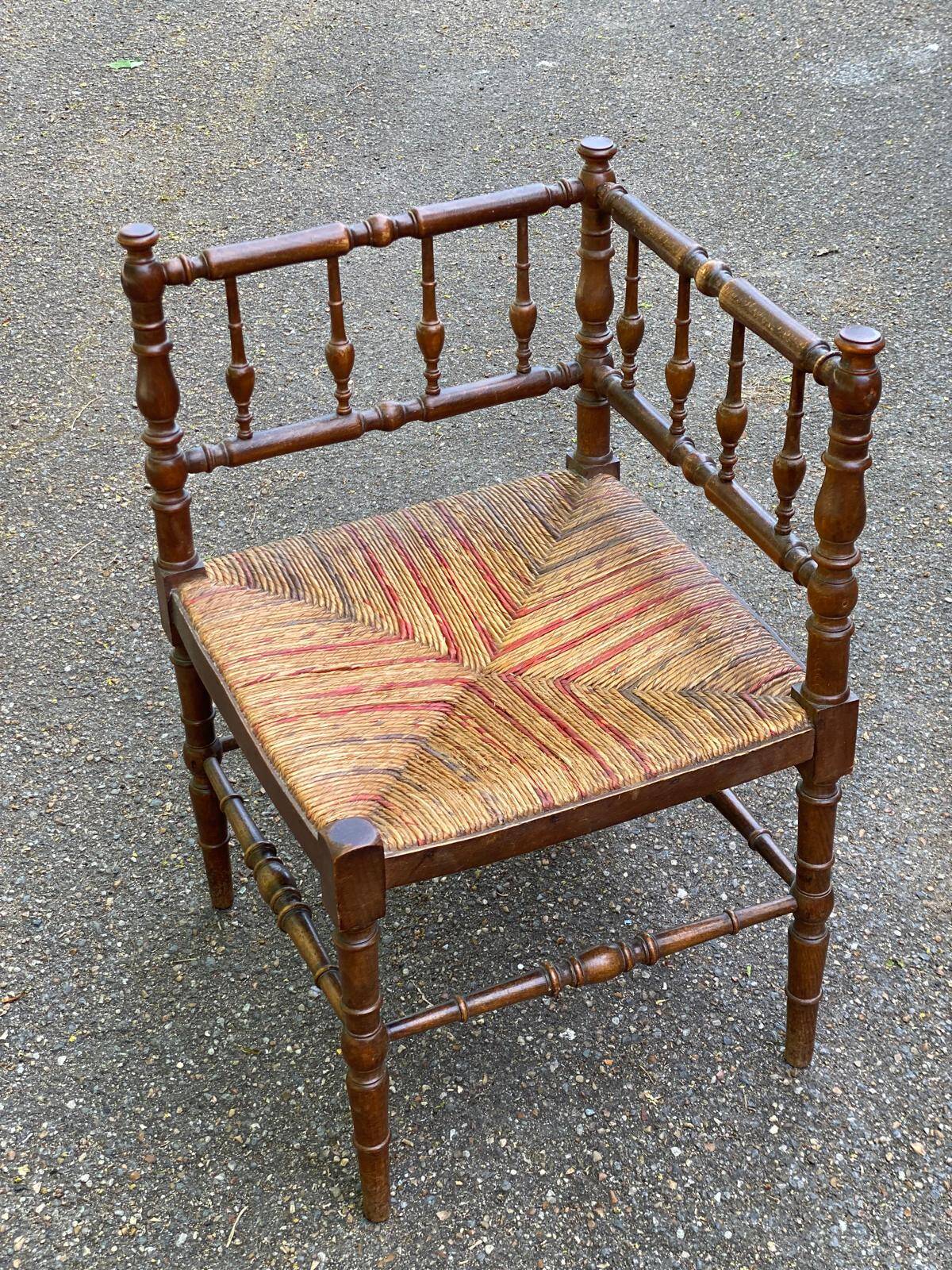 19th-century solid wood corner chair with red and blue rush seating.