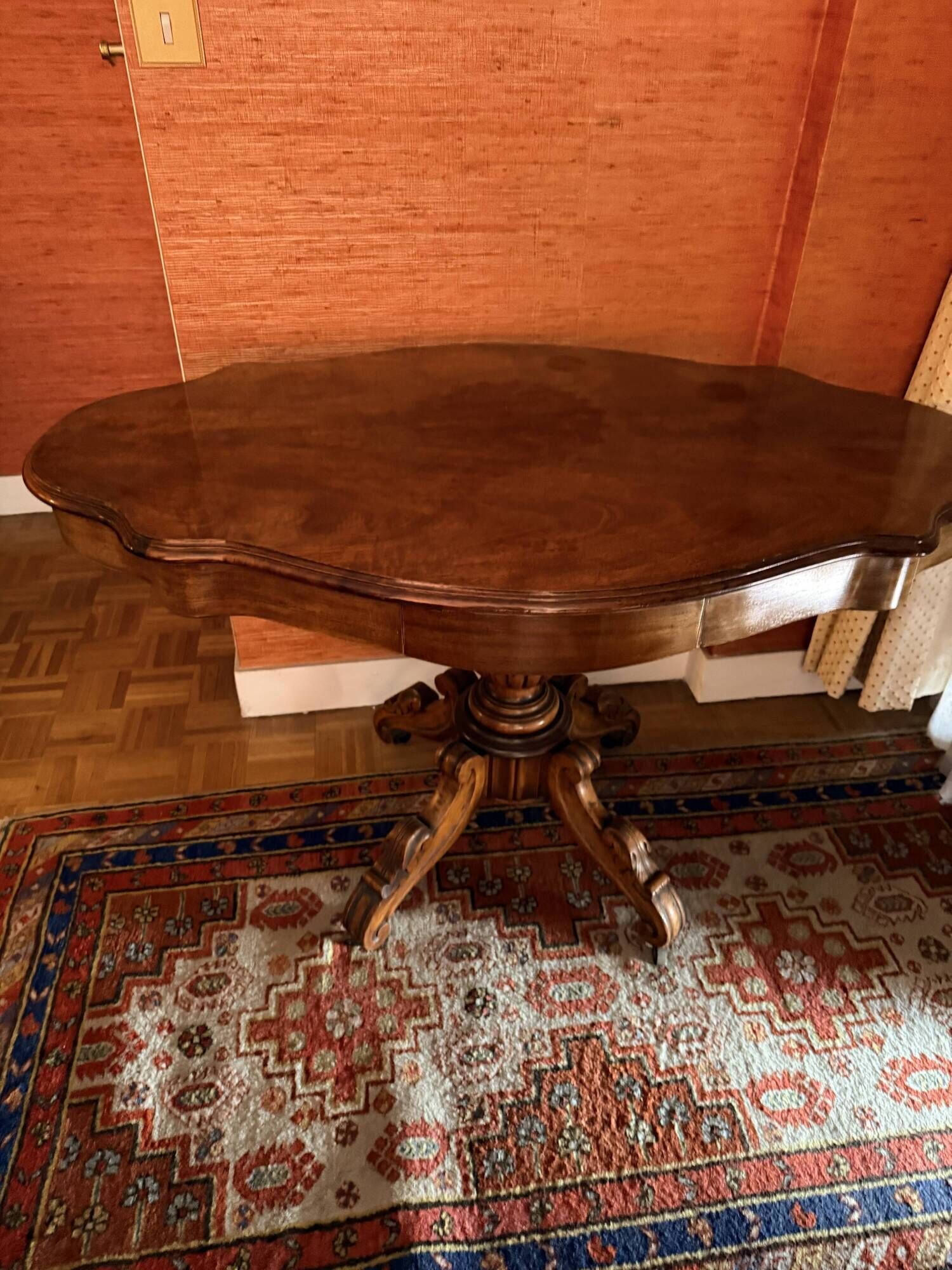 Antique mahogany table with a scalloped top and a sculpted central leg.
