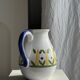 Large white terracotta carafe with a stylized green and yellow frieze pattern