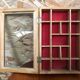 Old hanging display case with 15 wooden boxes, red background + vintage glass door