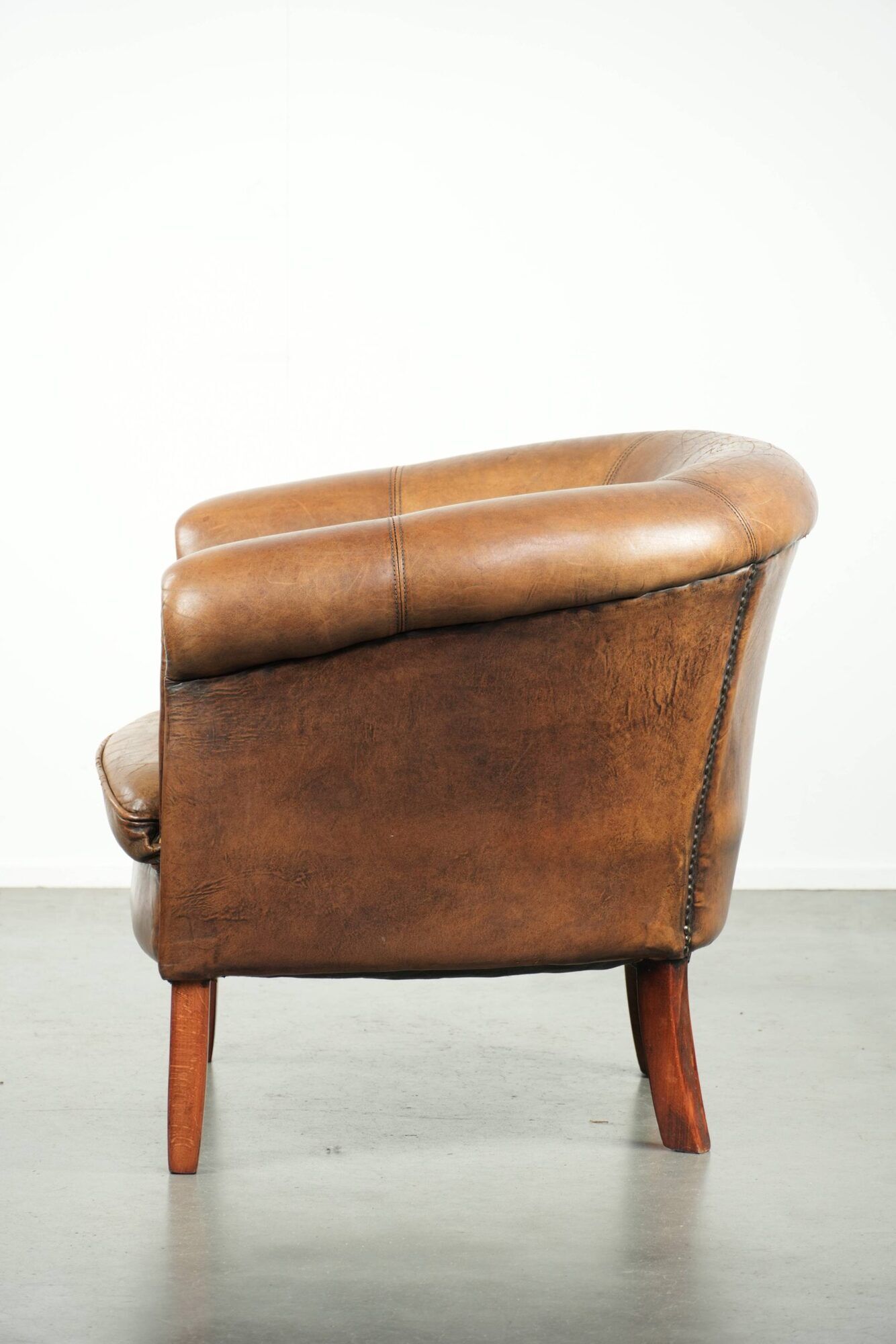 Sheepskin club armchair in a brown colour finished with decorative nails