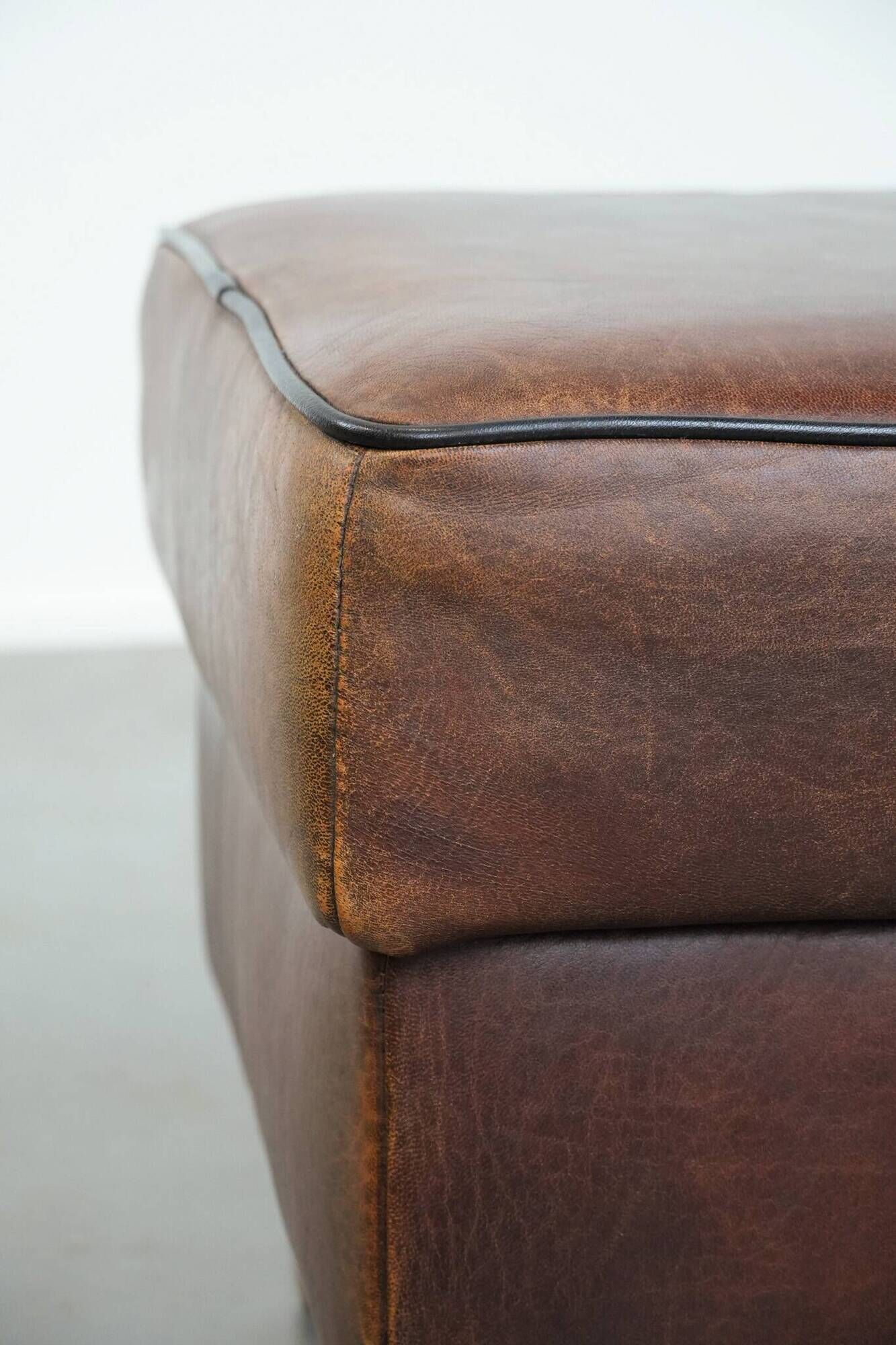 Sturdy vintage sheepskin ottoman in a beautiful large size with black piping