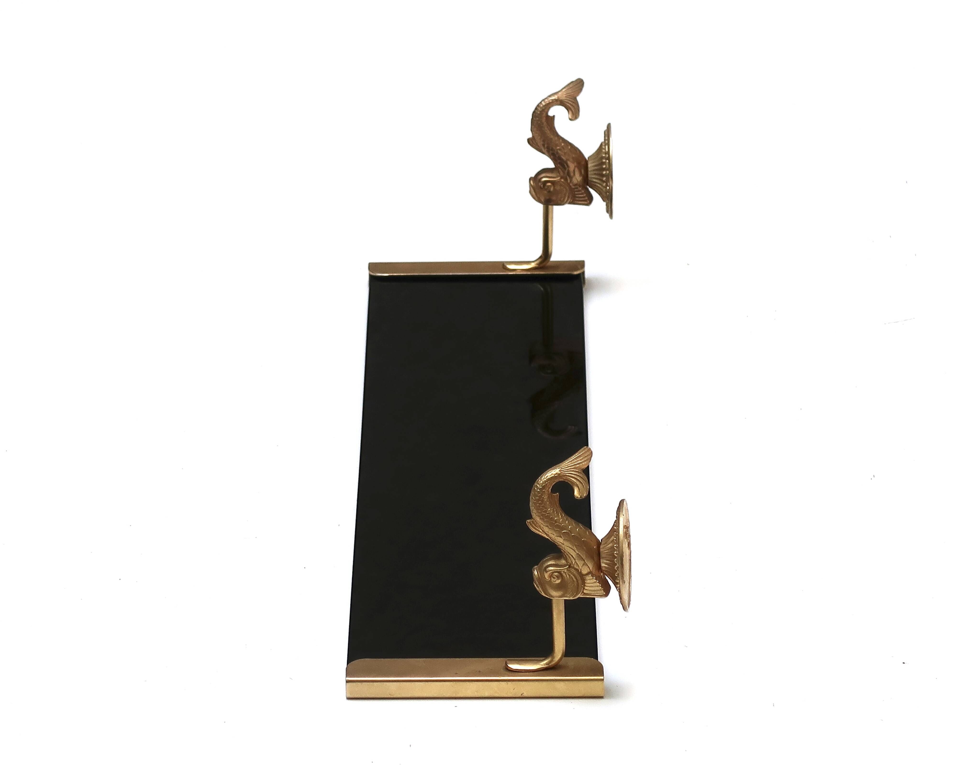 Wall shelf in gold metal and black glass adorned with fish.